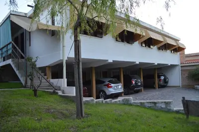 a building with cars parked in a parking lot at Hostería Los Sauces in Mina Clavero