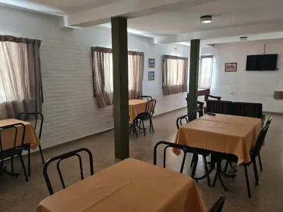 a dining room with tables and chairs and a tv at Hostería Los Sauces in Mina Clavero