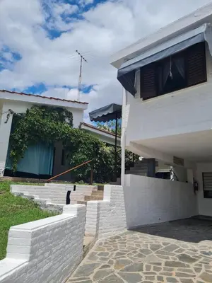 a white house with a brick walkway next to a building at Hostería Los Sauces in Mina Clavero