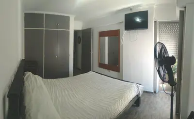 a bedroom with a white bed and a fan at Alquiler día Nueva Cordoba in Cordoba