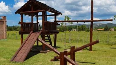 a wooden playground with a swing set in a field at Holiday Home Alta Vista in Mina Clavero