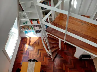 a staircase in a house with wooden floors and a book shelf at Dúplex de Diseño en Nueva Córdoba in Cordoba
