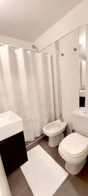 a white bathroom with a toilet and a sink at Departamento zona Tribunales in Cordoba
