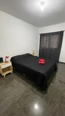 a bedroom with a black bed with a red bag on it at DEPARTAMENTO en VILLA CARLOS PAZ 4P in Villa Carlos Paz