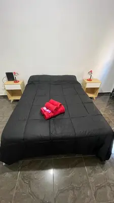 a black bed with red gloves on top of it at DEPARTAMENTO en VILLA CARLOS PAZ 4P in Villa Carlos Paz