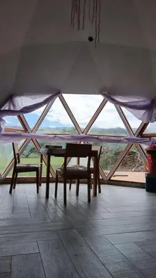 a table and two chairs in a room with a large window at Amawa Domo - escapada romántica en las sierras in San Francisco del Monte de Oro