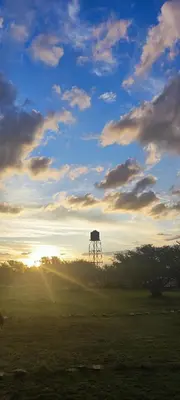 a sunset in a field with a water tower in the distance at Amawa Domo - escapada romántica en las sierras in San Francisco del Monte de Oro