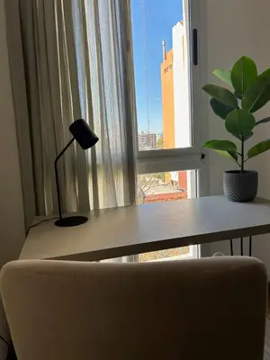 a desk with a lamp and a plant in front of a window at Departamento balcones de Cofico in Cordoba