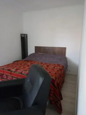 a bedroom with a bed with a chair next to it at Casa en Villa Los Aromos cerca del río in Villa Los Aromos