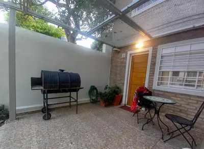a patio with a table and a grill and a house at Dúplex 250ms Peatonal in Villa Carlos Paz