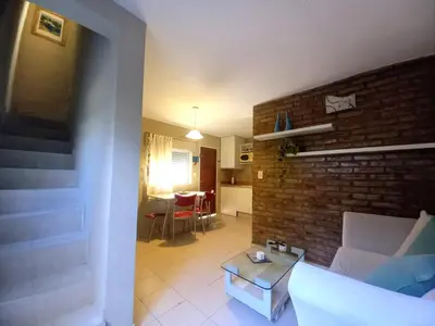 a living room with a couch and a brick wall at Dúplex 250ms Peatonal in Villa Carlos Paz