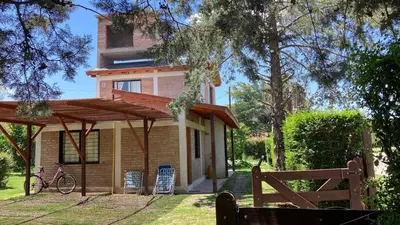 a house with a wooden pergola in front of it at La Maga in Santa Rosa de Calamuchita