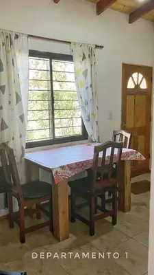 a table and chairs in a room with a window at La Maga in Santa Rosa de Calamuchita