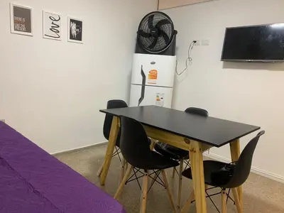 a table with chairs and a refrigerator in a room at Departamento Costanera in Villa Carlos Paz