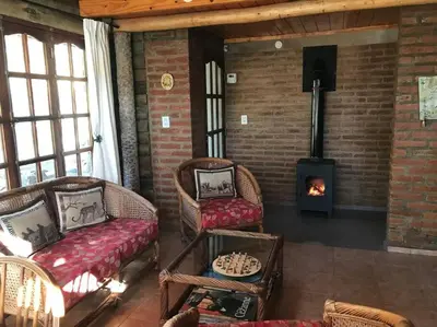 a living room with wicker chairs and a fireplace at Cabaña La Cotita in Villa Los Aromos