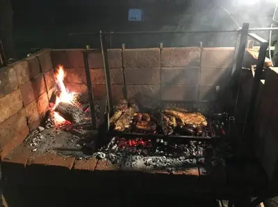 a large grill with meat and fire in it at Cabaña La Cotita in Villa Los Aromos