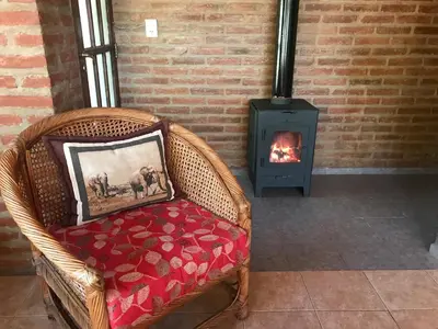 a wicker chair sitting in front of a fireplace at Cabaña La Cotita in Villa Los Aromos