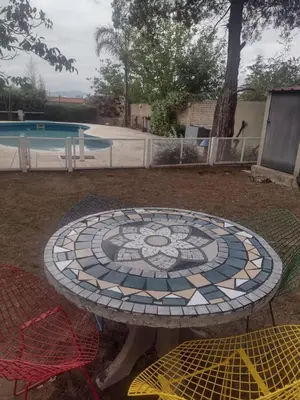 a table with a mosaic design on it next to a pool at Bialet Masse hermosa casa con pileta in Cordoba