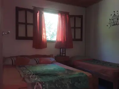 a bedroom with two beds and a window with red curtains at Cabañas La Fiaca in Los Manantiales