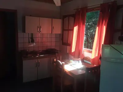 a kitchen with red curtains and a table and a window at Cabañas La Fiaca in Los Manantiales