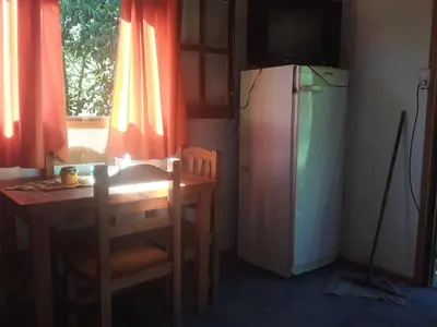 a kitchen with a small table and a refrigerator at Cabañas La Fiaca in Los Manantiales