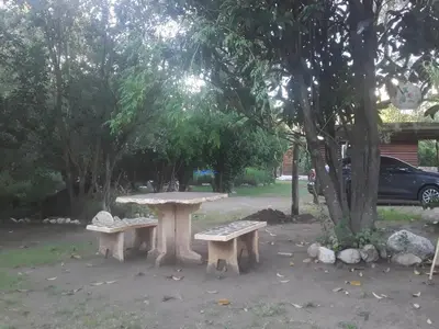 a picnic table and two benches under a tree at Cabañas La Fiaca in Los Manantiales