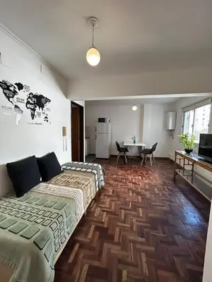 a room with two beds and a table and a kitchen at Departamento Nueva Cordoba in Cordoba