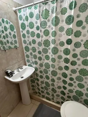 a bathroom with a shower curtain with a toilet and a sink at Departamento Nueva Cordoba in Cordoba