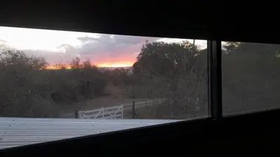 a view of a sunset from the window of a house at Siu Kiu - Casa de Montaña in El Parador