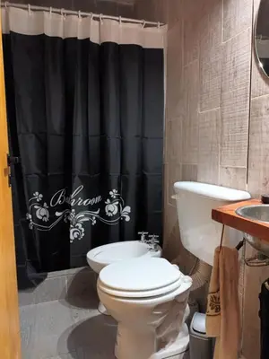 a bathroom with a toilet and a black shower curtain at Siu Kiu - Casa de Montaña in El Parador