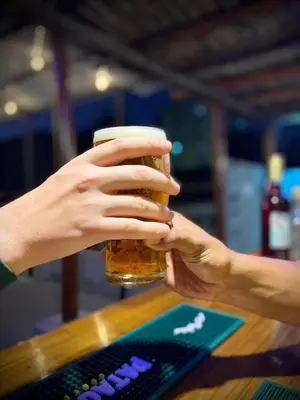 a person holding a glass of beer next to a keyboard at Hostel Alvear in Cordoba