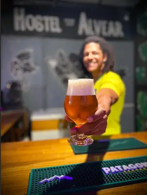 a woman is holding a glass of beer at Hostel Alvear in Cordoba