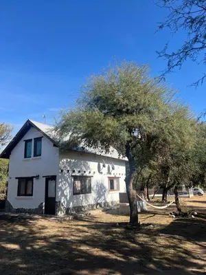 a white house with a tree in front of it at Cabañas La Felicidad in Merlo