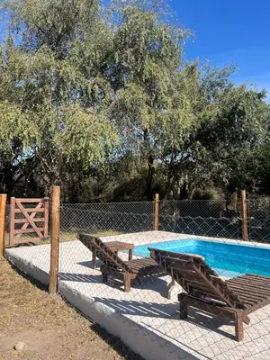 two wooden benches sitting next to a swimming pool at Cabañas La Felicidad in Merlo
