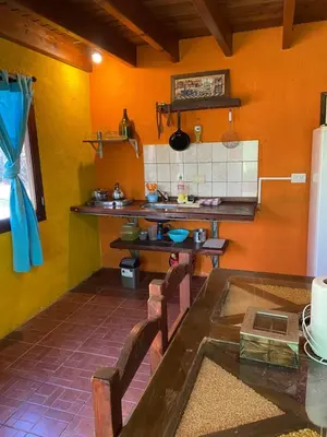 a kitchen with orange walls and a table with chairs at Cabañas La Felicidad in Merlo