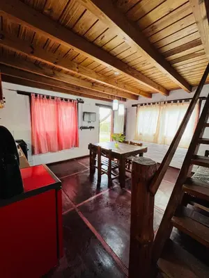 a room with a wooden table and red curtains at Cabañas La Felicidad in Merlo