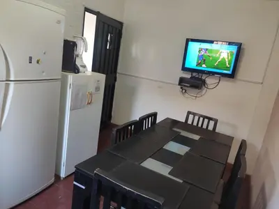 a kitchen with a table and a television on a wall at Depto mina clavero Córdoba zona residencial in Mina Clavero