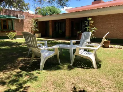 three white chairs and a table in a yard at Hotel Complejo Najul Suites-Solo Adultos in Mina Clavero