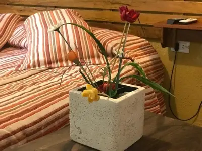 a white vase with flowers on a table next to a bed at Hotel Complejo Najul Suites-Solo Adultos in Mina Clavero