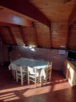 a table and chairs in a room with a brick wall at Alpinas San Lorenzo in Merlo