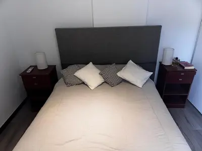 a bed with three pillows on it with two night stands at Magnolia in Cordoba