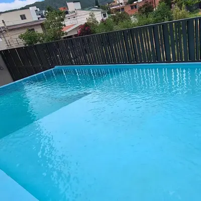 a large blue swimming pool next to a fence at Sundara Tan perfecto que no vas a querer irte in Villa Carlos Paz