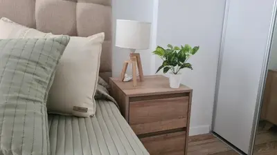 a bed with a table with a lamp and a plant at Sundara Tan perfecto que no vas a querer irte in Villa Carlos Paz
