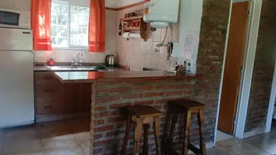 a kitchen with a brick counter and stools in it at Cabañas El Duende in Quines