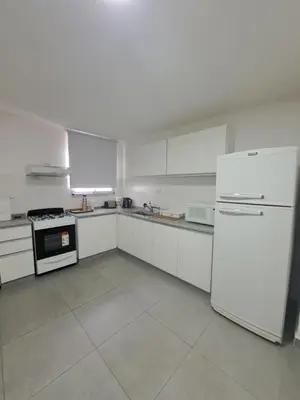 a white kitchen with white appliances and white cabinets at Departamento -Roma- Barrio General Paz - A una cuadra de 24 de septiembre y enfrente del Polideportivo By Apartcba in Cordoba