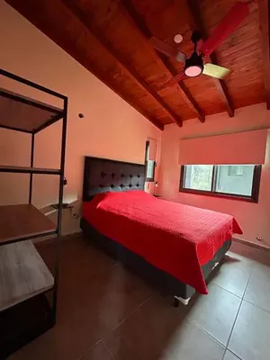 a bedroom with a red bed and a ceiling fan at Cabañas La Arbolada in El Durazno