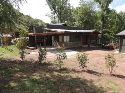 a house with trees in front of it at Cabañas La Arbolada in El Durazno