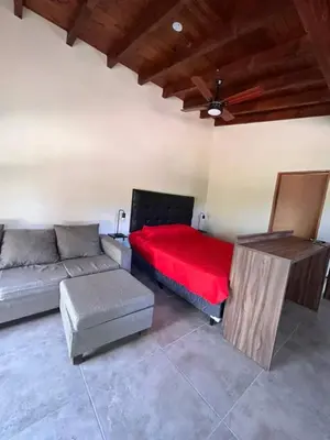 a living room with a couch and a red bed at Cabañas La Arbolada in El Durazno