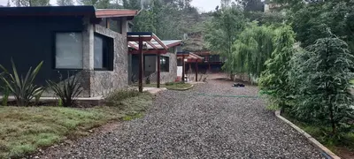a gravel path next to a house with a green hose at Cabañas La Arbolada in El Durazno