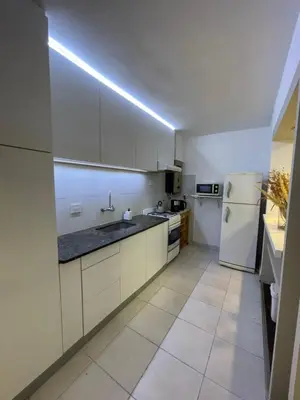 a kitchen with white cabinets and a white refrigerator at Departamento PB, patio y asador privados - NUEVO SERVICIO Estacionamiento 24hs INCLUIDO, no camioneta- Cerca de hotel Quinto Centenario, Nuevocentro shopping, Hospital Clinicas y Club Universitario Córdoba Sede central in Cordoba